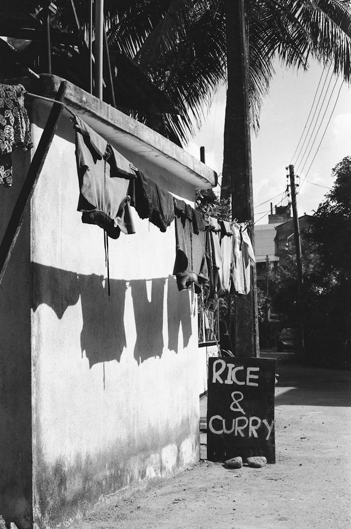 Black and white image of laundry drying on a wall with a rice & curry sign below.
