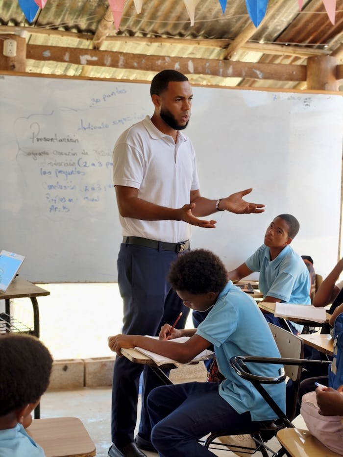 A teacher leads a lesson with attentive students in an informal classroom setting.